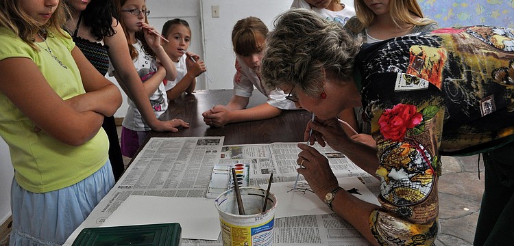Charlotte Smith shows the class how to blow through the straw lightly in order to make the paint look like tree limbs Friday, July 8 at the Art and Photography Studio of Colleen Cassidy.