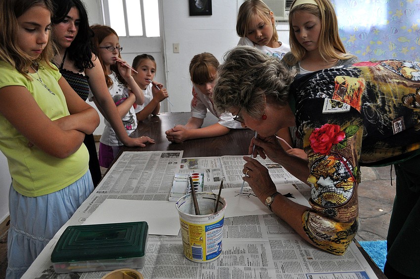 Charlotte Smith shows the class how to blow through the straw lightly in order to make the paint look like tree limbs Friday, July 8 at the Art and Photography Studio of Colleen Cassidy.