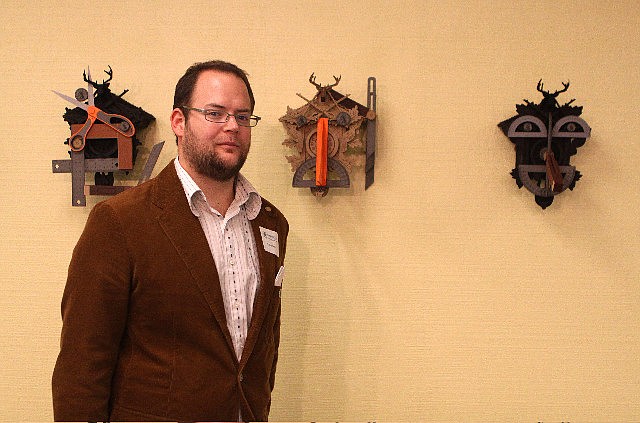 Nathan Skiles poses in front of a few of his pieces featured in the exhibit.