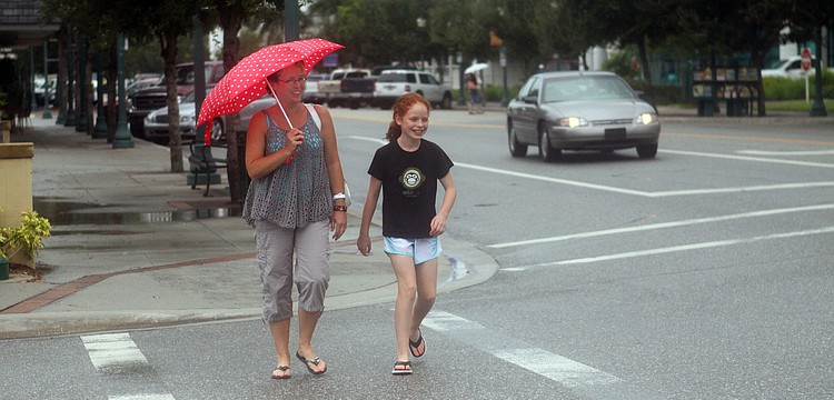 Lisa Knopp and her daughter, Grace, 11, walk to the bank in the rain after having lunch Wednesday, August 10 at Barnacle Bill's downtown.