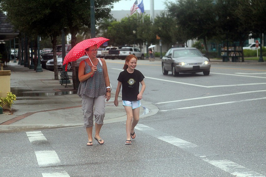 Lisa Knopp and her daughter, Grace, 11, walk to the bank in the rain after having lunch Wednesday, August 10 at Barnacle Bill's downtown.