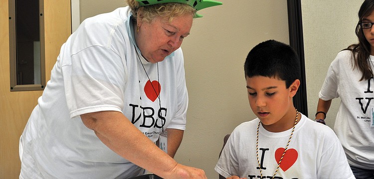 Posy Havens helps McNeal Elementary third-grader Gabe Hahn with his craft project.