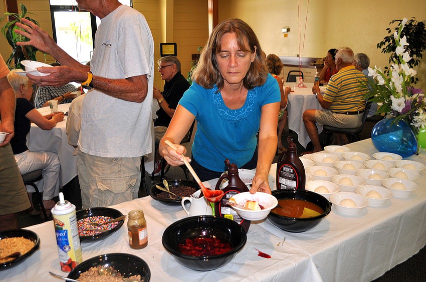 Joann McManus puts some strawberries on top of her ice cream Sunday, August 14 during the ice cream social in the Parish Hall at St. Boniface.