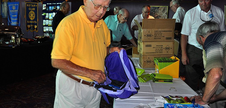 Art Hamilton begins to fill up a purple backpack with school supplies.