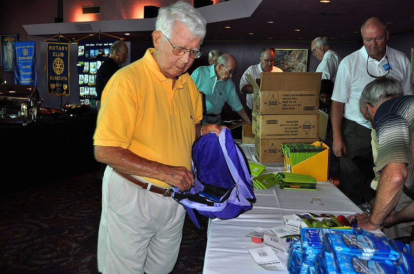 Art Hamilton begins to fill up a purple backpack with school supplies.