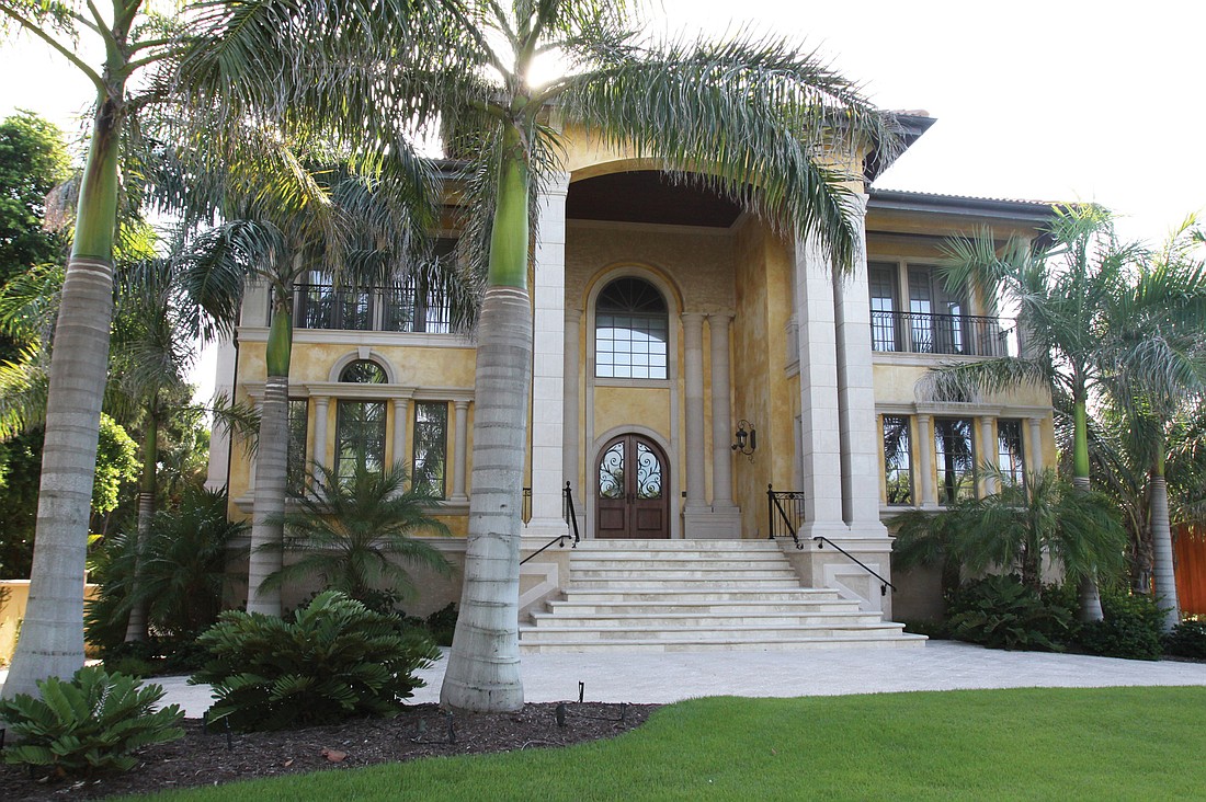 The front of the Casey Key home is surrounded by palm trees and other foliage.