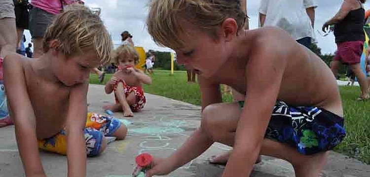 Matthew Vanderkooy, right, plays with chalk with his brothers, Caleb, left, and Nathaniel, behind.