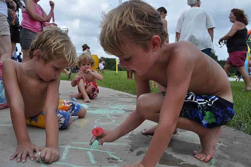 Matthew Vanderkooy, right, plays with chalk with his brothers, Caleb, left, and Nathaniel, behind.