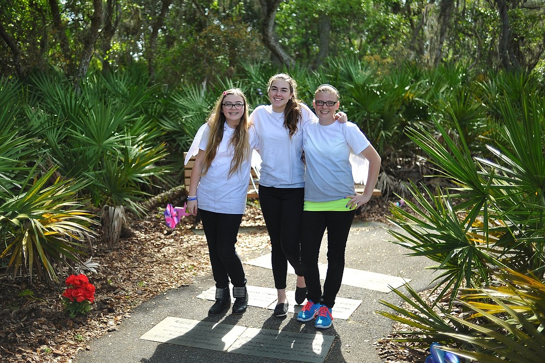 Indian Trails Middle School students Olivia Reynolds, Christina Cabada, and Erin Robinson pose for a portrait in the Children's Memorial Garden at Waterfront Park. (Photo by Joey LoMonaco)