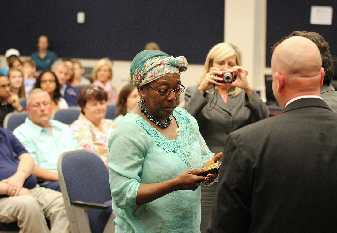 Marian Irvin receives her Power of One Award from school board chairman Andy Dance and superintendent Jacob Oliva.