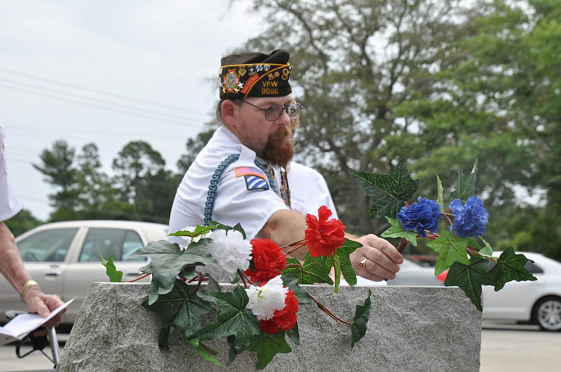 VFW Post 8696 Cmndr. Ron Stark places flowers on a memorial to symbolize truth and fedelity.