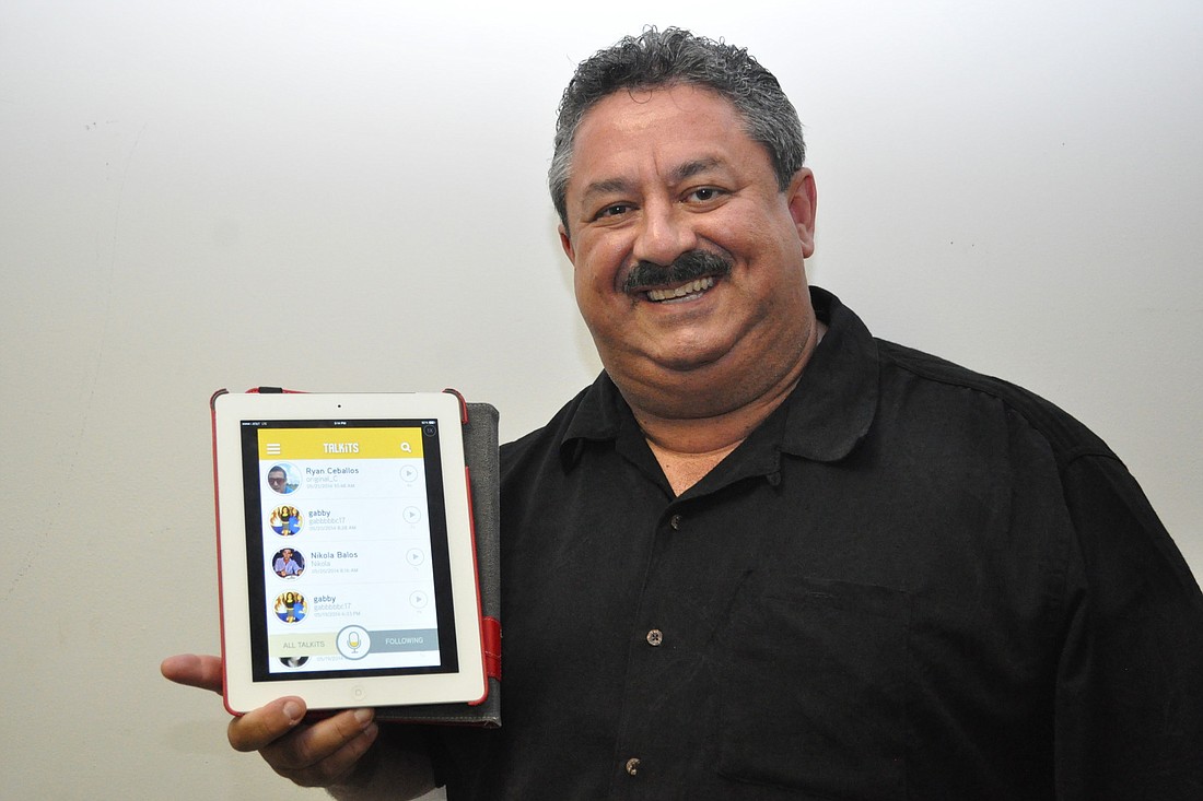 TALKiT creator Curtis Ceballos holds up an iPad showing a prototype of his new app, TALKiT. (Photo by Jonathan Simmons)