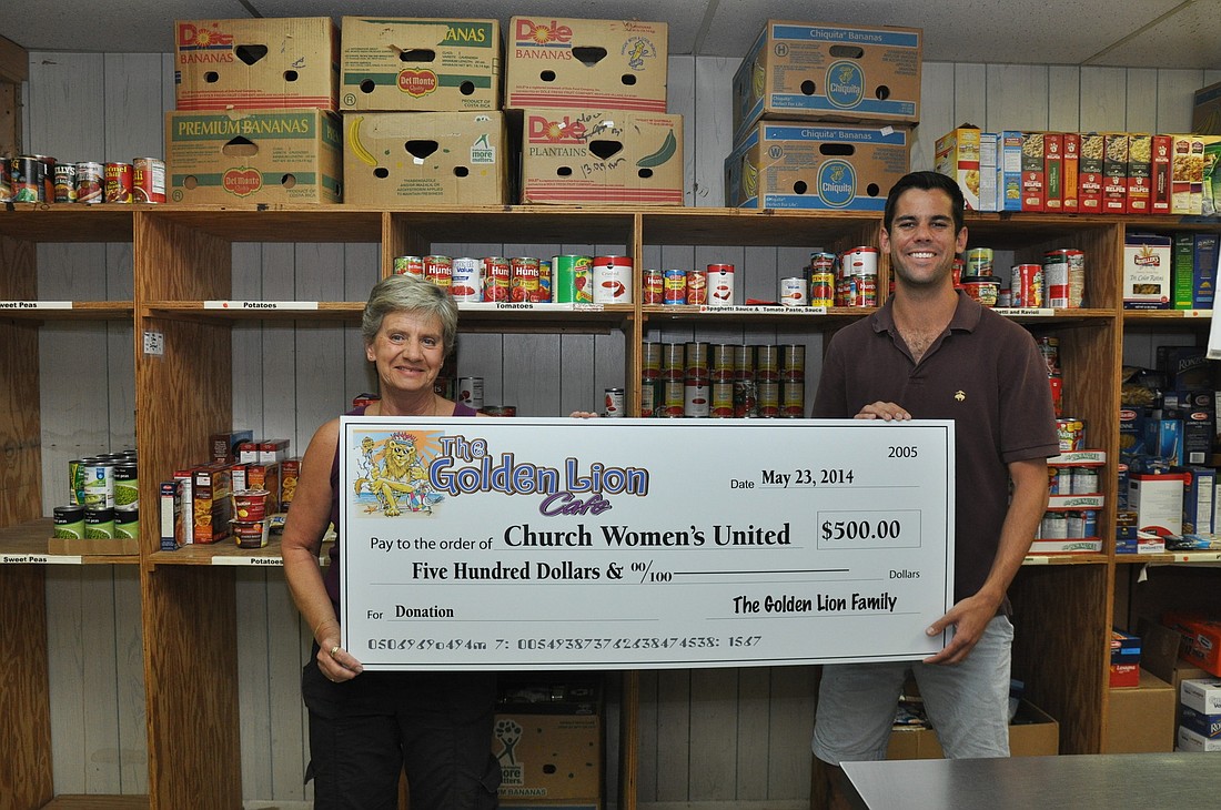 Barbara Royere, volunteer, accepts a $500 donation on behalf of the Resource Center in Bunnell from Chris Marlow, of the Golden Lion. PHOTOS BY SHANNA FORTIER