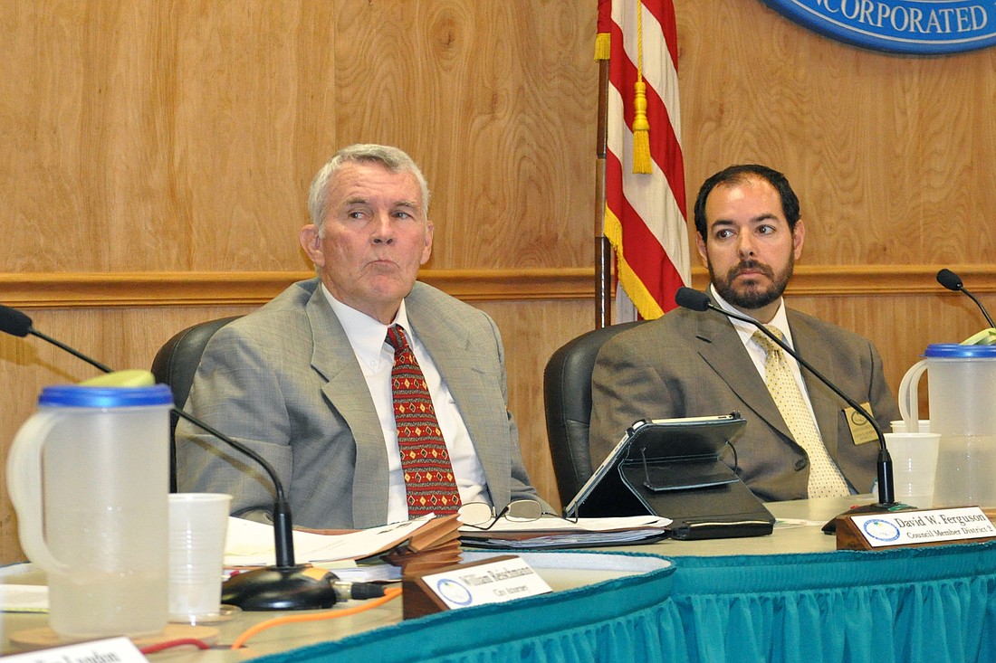 Palm Coast Councilmen David Ferguson and Jason DeLorenzo listen to City Manager Jim Landon speak about the city's red-light camera program during a Jun 17 council meeting. (Photo by Jonathan Simmons)