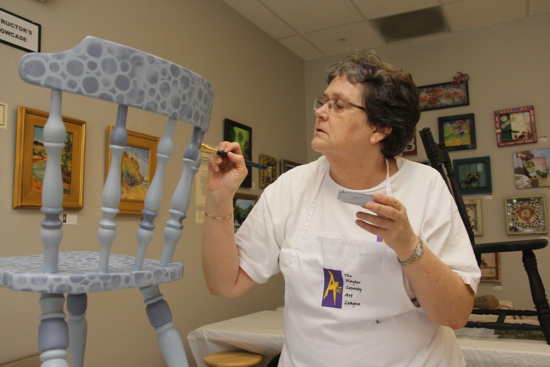 Judy Madigan puts the finishing touches on her chair at the Flagler County Art League gallery Saturday morning. PHOTOS BY SHANNA FORTIER