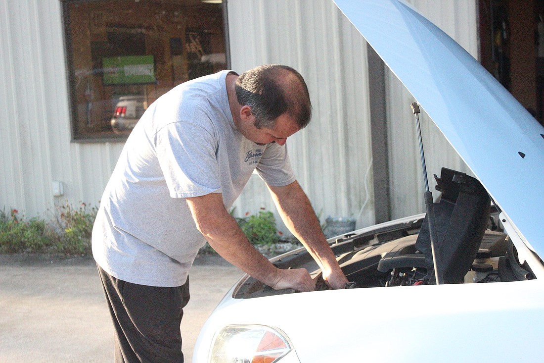 Paul Barrow works on a customer's car at his new shop on 13 Enterprise Drive.