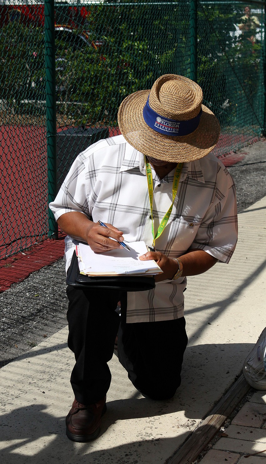 Ervin Shannon of the Manatee County Cooperative Extension writes down the exact height, 32 feet, of the cotton plant Friday, July 15 at Casa del Mar.