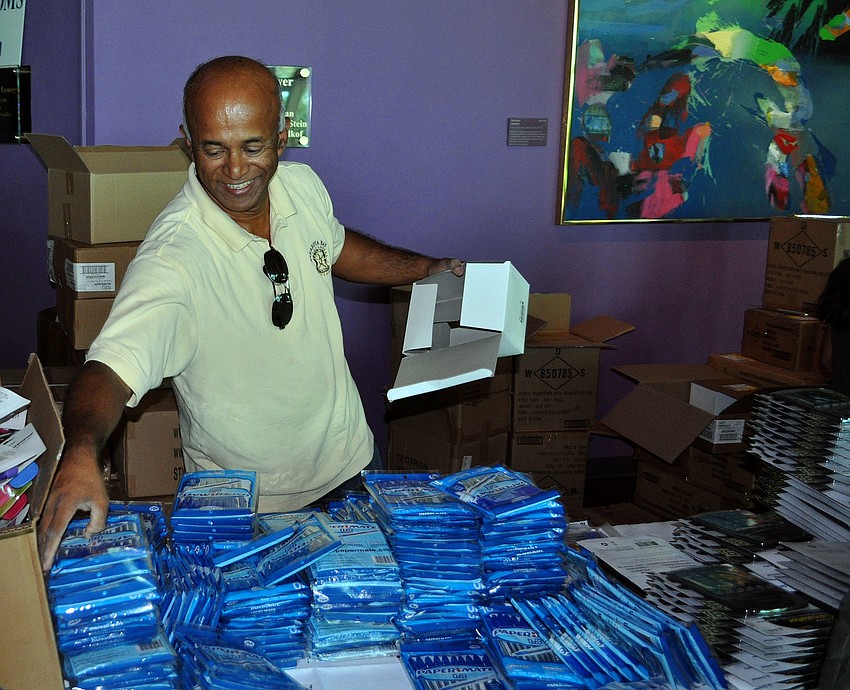 Dr. Ali Tahiri puts out more bags of pens onto the table to be added to the backpacks.