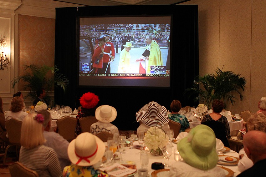 People watch Queen Elizabeth on TV and wore extravagant hats as part of the royal wedding party experience Friday, April 29 at the Ritz Carlton.