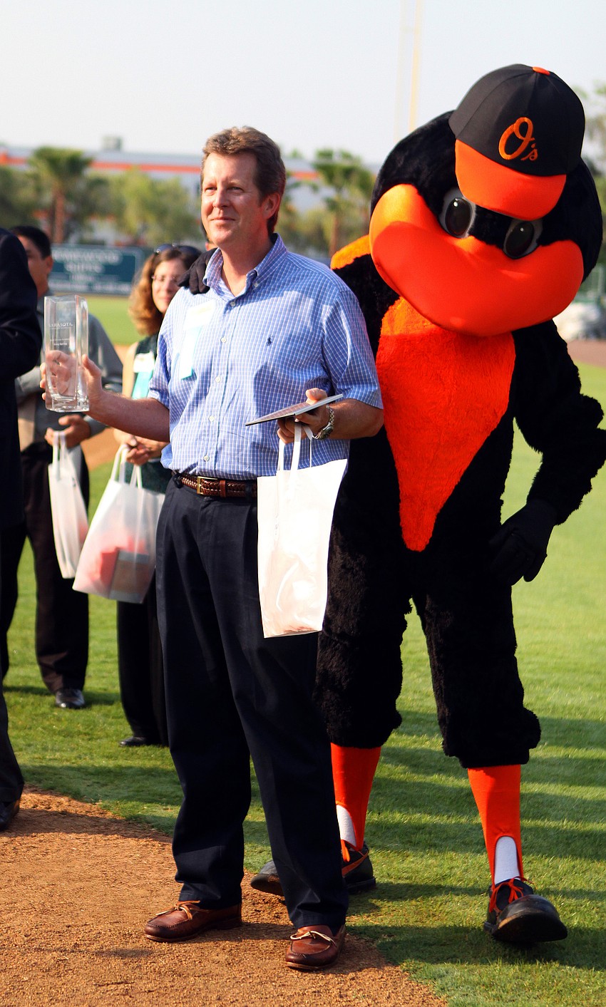 Greg Spring of Lakewood Ranch Communities holds up his award for Guest Service Excellence Front of the House - Vistor Services while posing by The Bird at the 2011 National Tourism Week Awards ceremony Thursday, May 12, at Ed Smith Stadium.