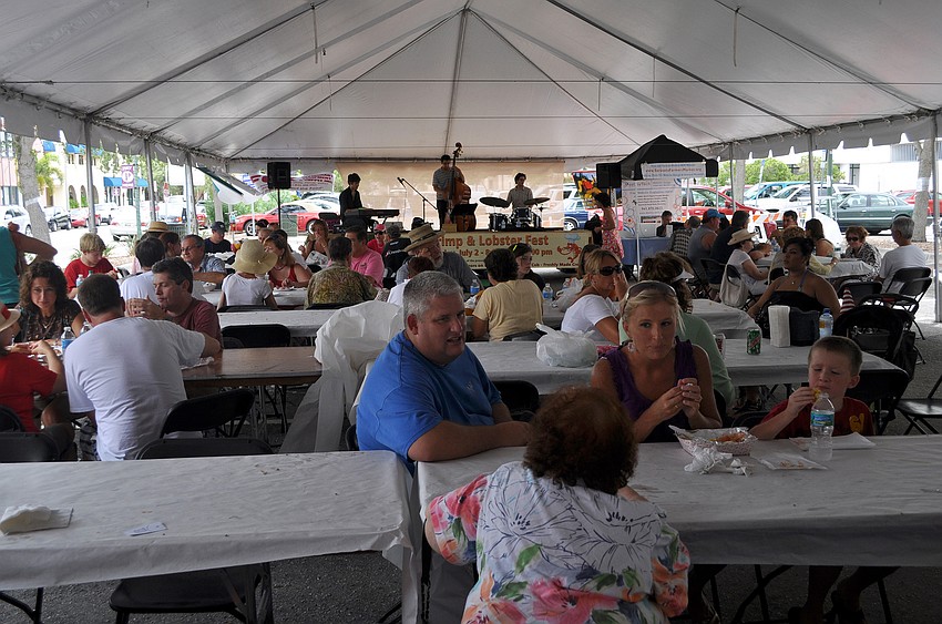 People enjoy sitting under the 100-foot tent while eating their seafood Saturday, July 2 at the Sarasota Farmers Market first ever Shrimp and Lobster Festival.