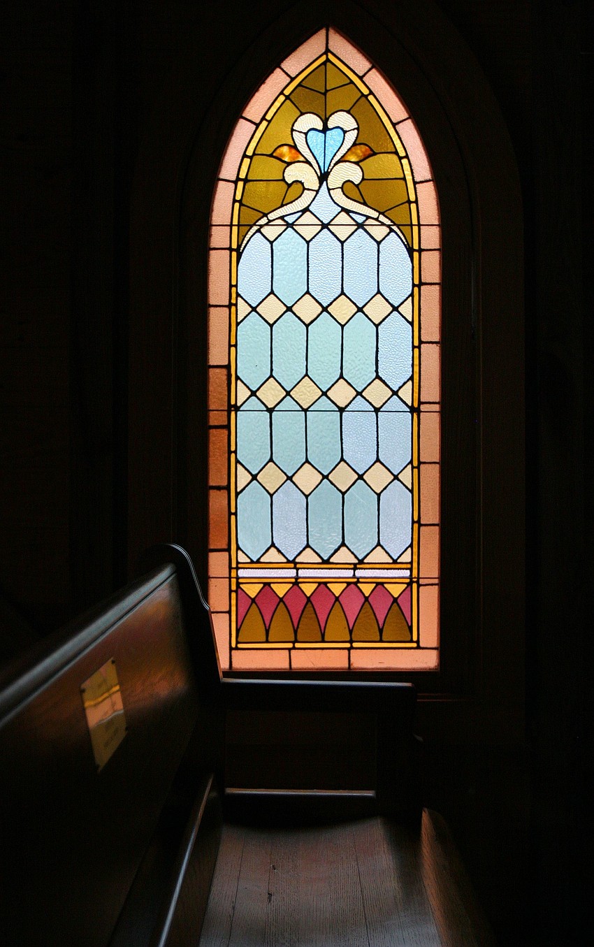A stain glass window at Maryâ€™s Chapel at Historic Spanish Point lets in some light into the dark chapel.