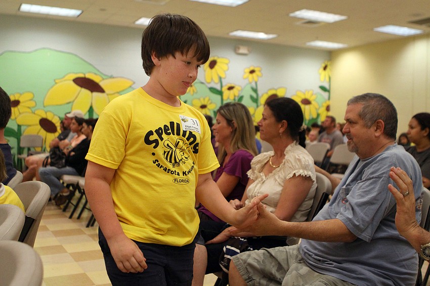 Elijah Firman gets high fives from his family as he makes his way back to the end of the line to be in the next round of the spelling bee.