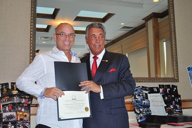 Michael Valentino accepts an award on behalf of the St. Armands Business Improvement District (BID) from St. Armands Circle Association President Andrew Vac.