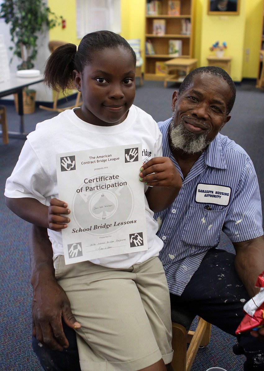 Jamilah Walker sits on her father's, Raymond, lap after receiving her Certificate of Participation Monday, May 23 inside Gocico Elementary School's Media Center. Walker also won a trophy for being one of the best bridge players in the club.