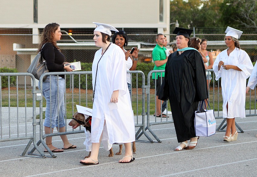 Emily Guttridge walks around the track with her medical alert dog, Roxie, Friday, June 3 at Sarasota High School's graduation at Cleland Stadium. Guttridge had a cap and gown created for Roxie to wear to graduation.