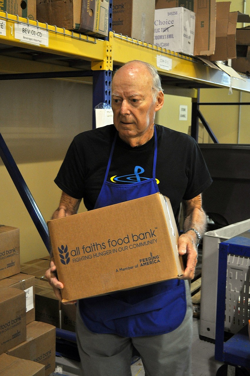 Bob Hambrecht carries boxes of cans that have already been packed at All Faiths Food Bank. Hambrecht and his wife, Carol, have been volunteering at All Faiths Food Bank for 14 years.Â