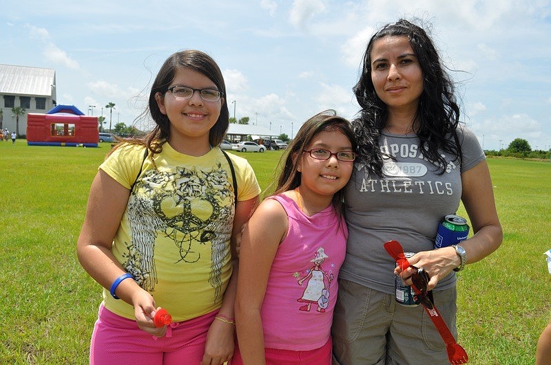 Melany Torres, with her sister Socorro and mom Susanna, watched her brother compete in the foot races.