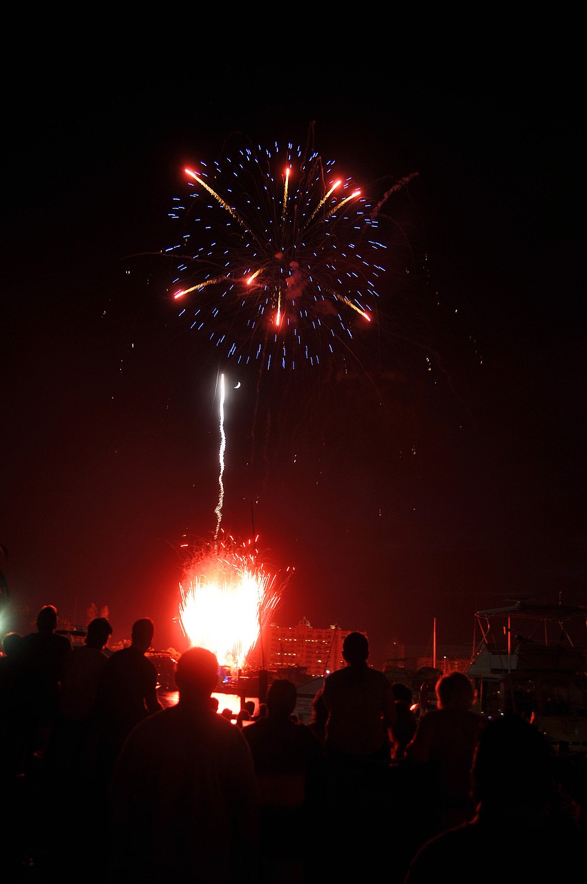 A red, blue and gold firework goes off as a ton of loud and smoky red fireworks go off below during the Bayfront Fireworks Spectacular Monday, July 4 at Island Park.
