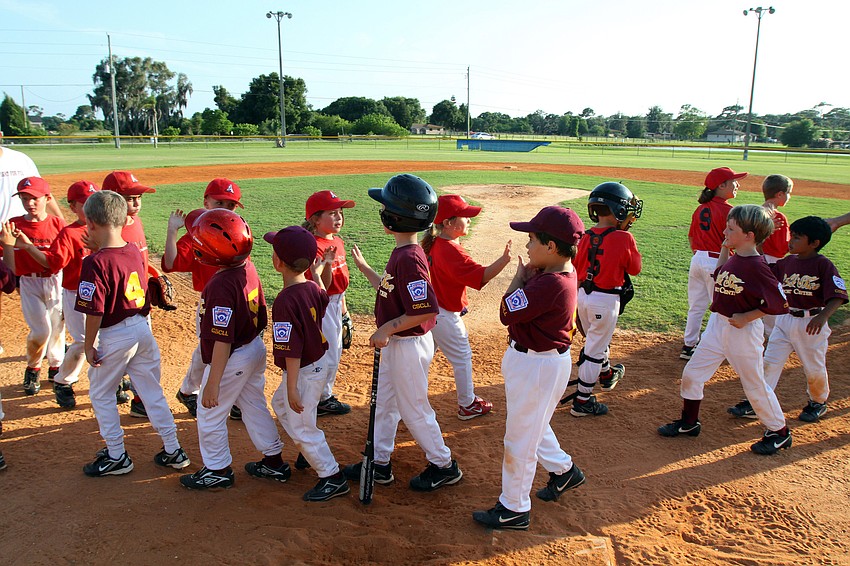 The Observer team and the Ball N Shoe team high five after their final game of the Spring season Monday, May 9 out at Twin Lakes Park.