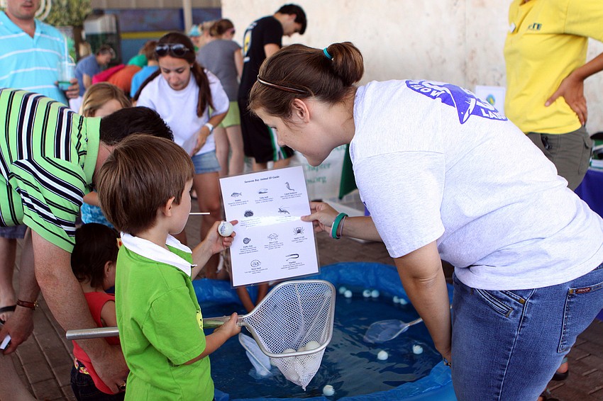 Isak Dubrow holds one of the ping pong balls with a sea creature picture on it and points to the corresponding picture on the sheet held by Heather Esfa during World Ocean Day Family Festival Sunday, June 5 at Mote Aquarium.