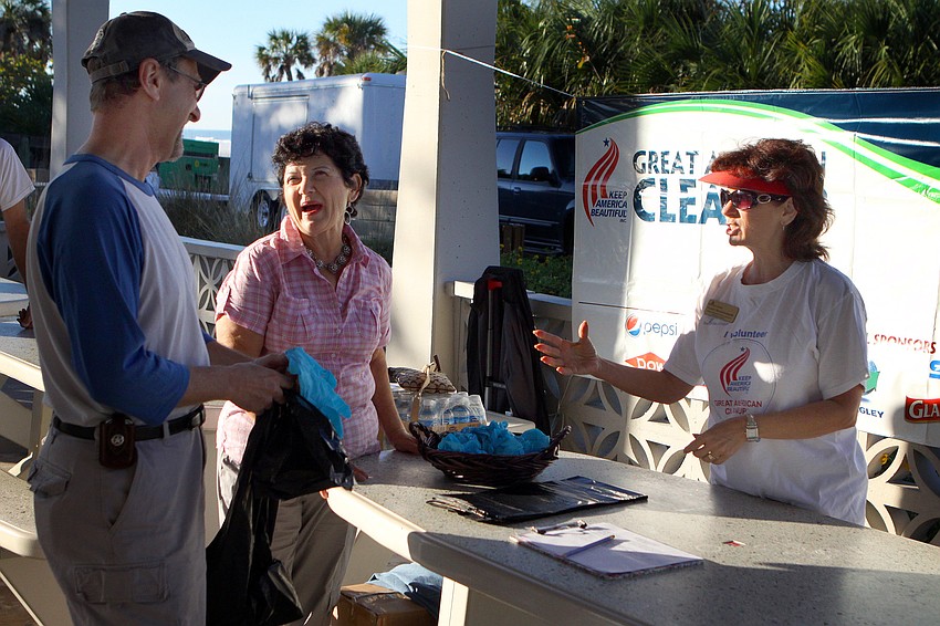 Kevin Smith gets blue gloves and trash bags from Rachele Farnum and Candi Messerschmidt.