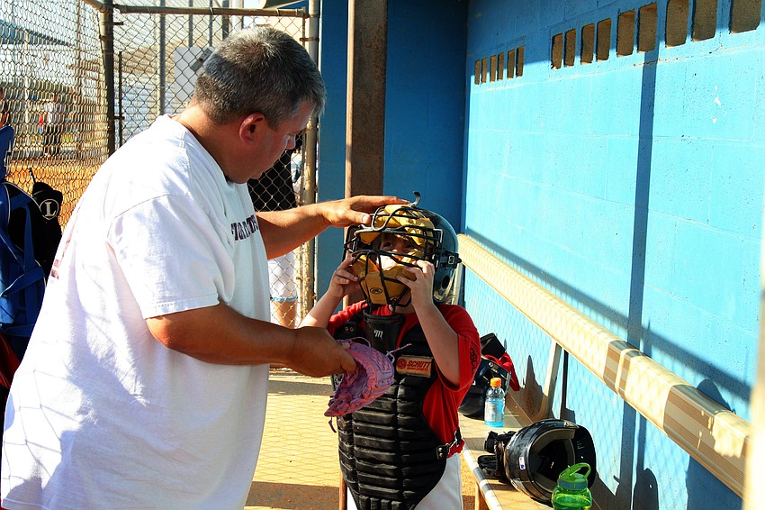 Coach Tim Enos helps Jada Totten, 6, get into the catcher's gear Monday, May 9 at Twin Lakes Park.