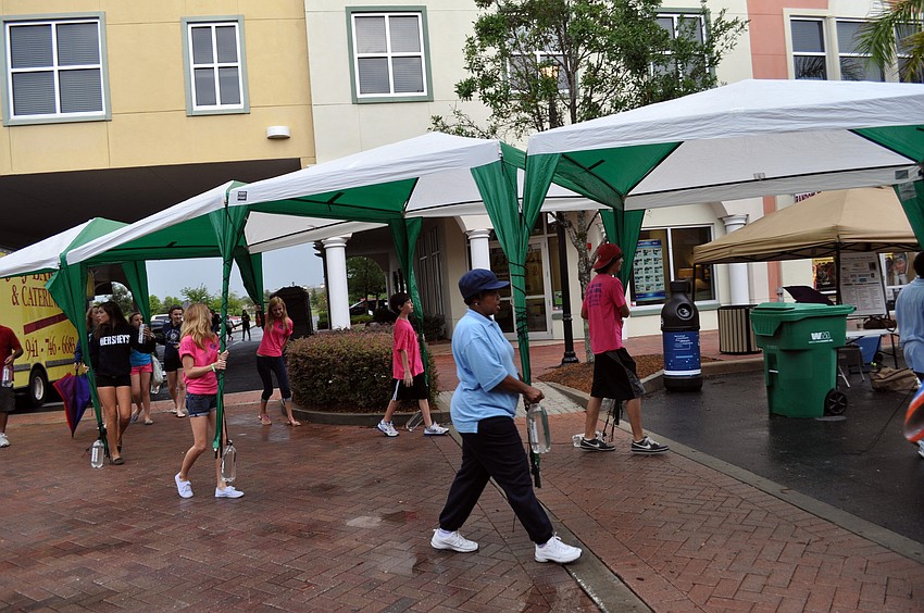Volunteers carry in more tents to help protect vendors from the rain.