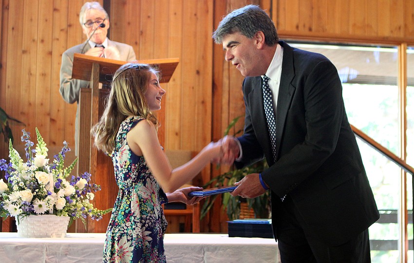 Caitlin Camire shakes hands with Headmaster Mahler while receiving the Academic Award Friday, June 3 during ODA's 6th grade graduation at Siesta Key Chapel.