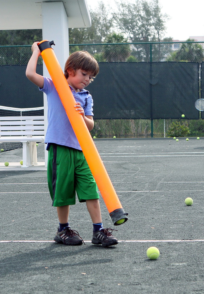 Charlie Tack, 5, picks up tennis balls with a tube during Longboat Key Club's Sports Camp Monday, June 6 at Longboat Key Club's Tennis Gardens.