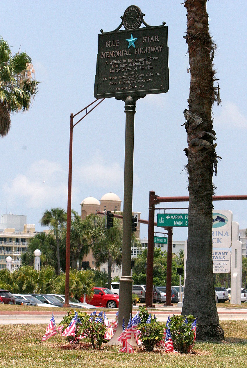Small, plastic American flags surround the bottom of the sign for the Blue Star Memorial Highway on Tuesday, June 14 in J.D. Hamel Park along Tamiami Trail. In the United States, Flag Day is celebrated on June 14.