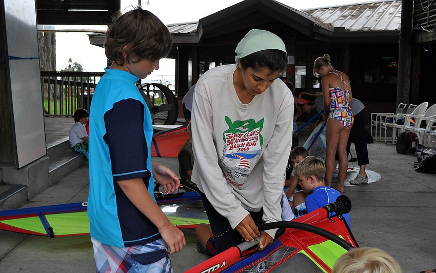 Ariana Abid helps Nick Burback, 12, put together one of the wind surfing sails during a learning exercise Friday, July 8 during the Island Style Water Sports Camp.