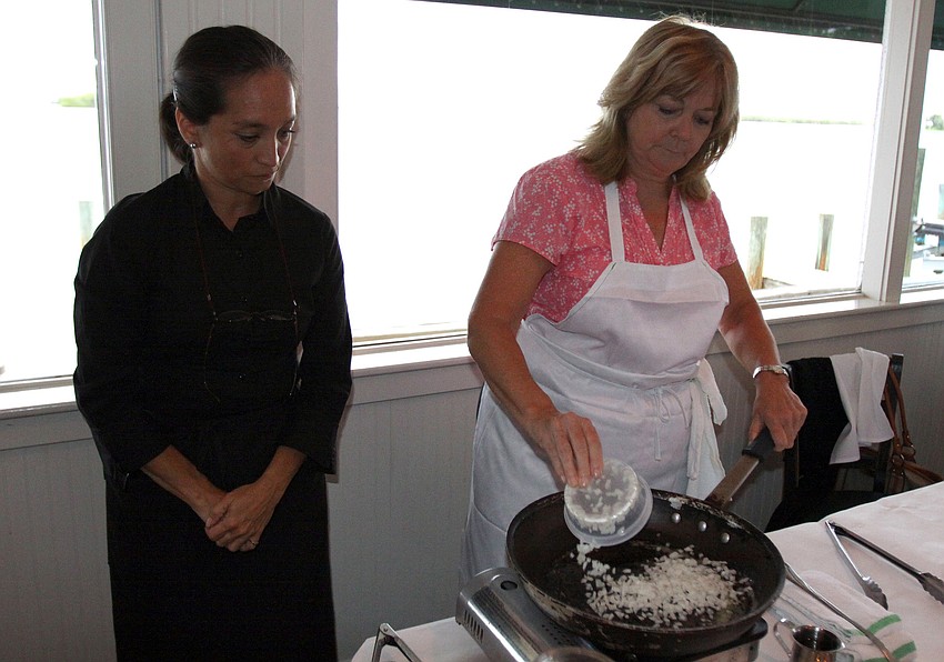 Kay Borge watches over Maureen Gillenâ€™s shoulder while she puts diced onions into the skillet Friday, July 22 during the Interactive Mexico dinner at Pattigeorgeâ€™s.