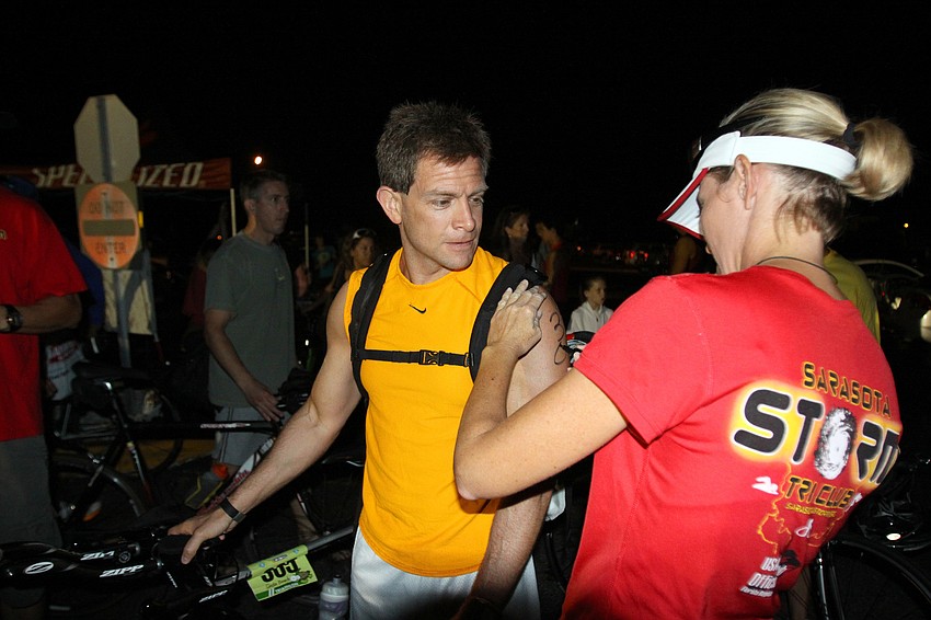 Steve Torres gets marked with his race number, 305, by Nicole Chapman early Saturday morning prior to the Siesta Key Triathlon.