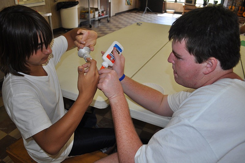 Camper Caleb Anderson and counselor Paul Haas work on a torch for their trophy.