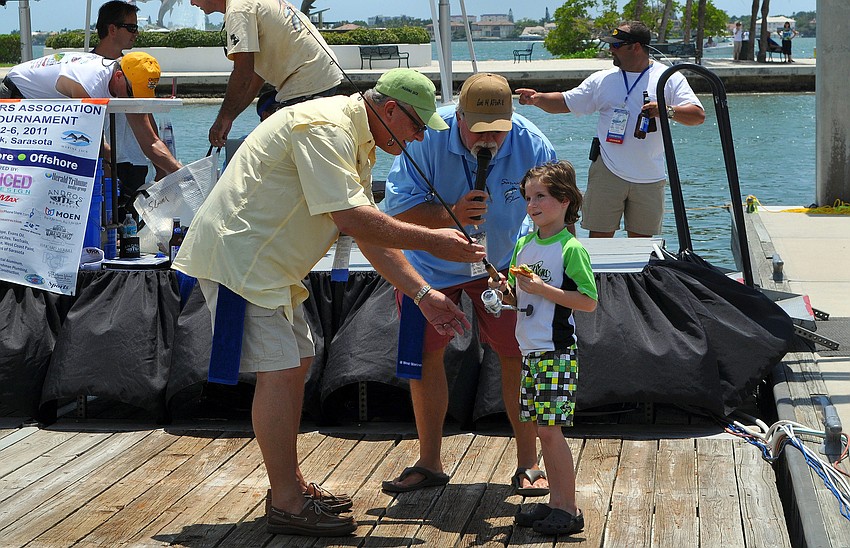 M.C. Mark Gauthier talks to Kai Hunkeler about the fishing rod given to him by Alan Anderson, left, Saturday, August 6 during the Sarasota Slam weigh-in at Marina Jackâ€™s.