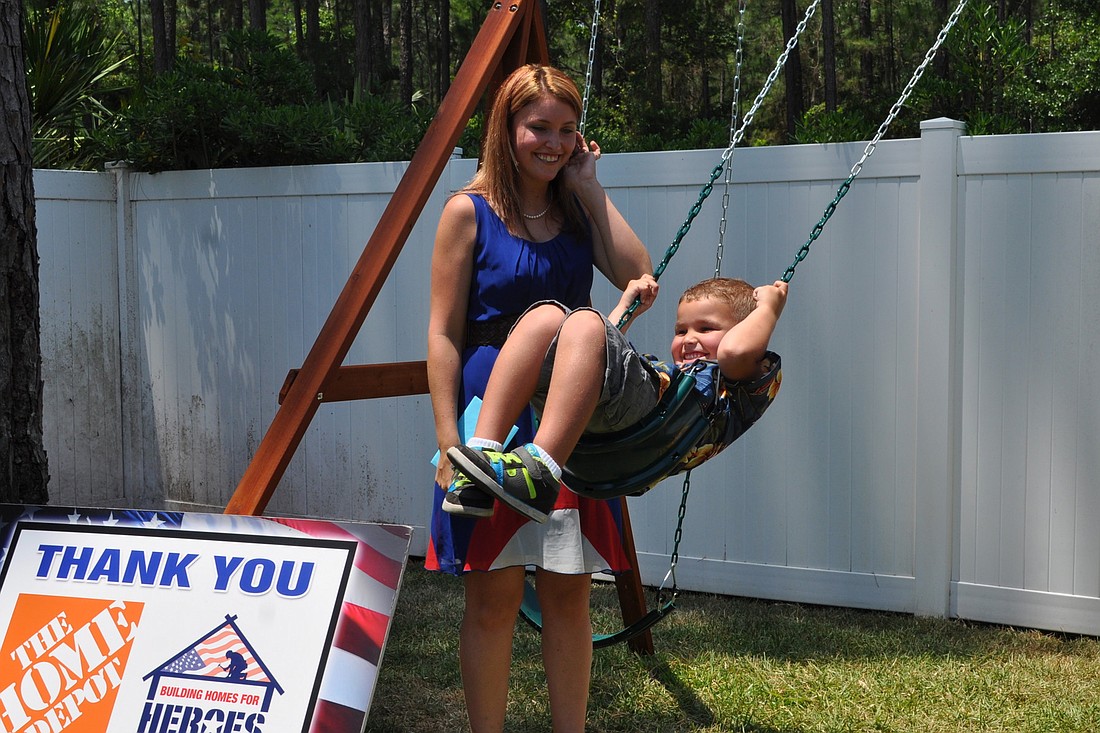 Kate Denker swings her 4-year-old son Freddy on the new swing set in their new home, provided through Building Homes for Heroes. (Photo by Jonathan Simmons.)