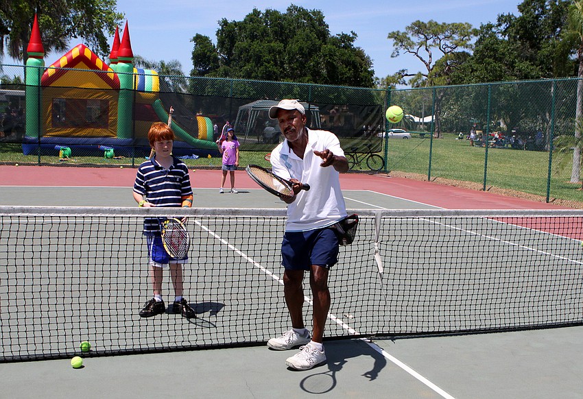 Tennis pro Cliff Vines shows Connor Mayor, 9, how to properly hit a tennis ball during a the free tennis lesson that was given on Sunday, April 17 during South Bay's Family Fun Day.