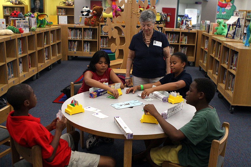 Booker Middle School's bridge club advisor, Jane Huerta, helps Jamiliah Walker with her next move during the bridge club's final meeting Monday, May 23 inside Gocico Elementary School's Media Center.