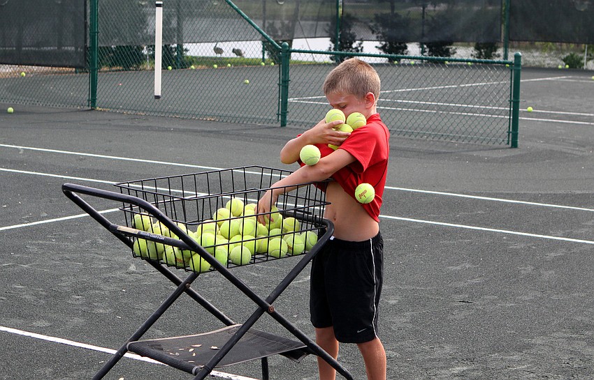 Jackson Dunham, 7, filled his shirt with tennis balls and attempts to empty them all into the basket during Longboat Key Club's Sports Camp Monday, June 6 at Longboat Key Club's Tennis Gardens.